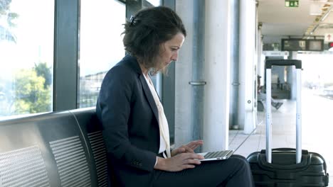 Businesswoman-working-with-laptop-at-railway-station